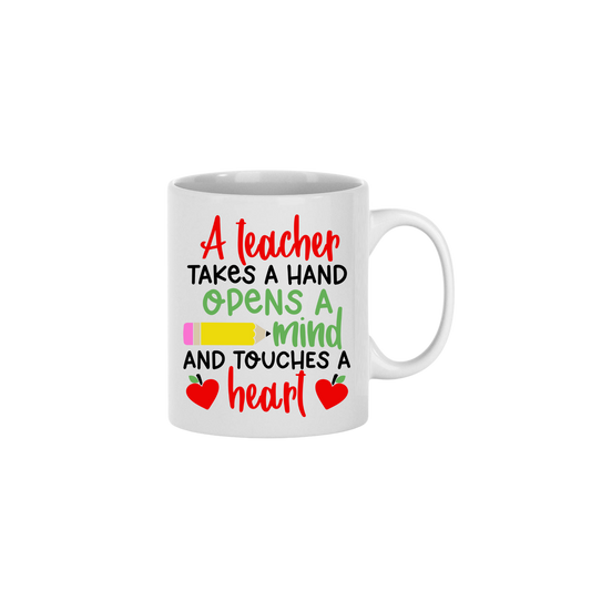 A white ceramic mug with text that reads 'A teacher takes a hand, opens a mind, and touches a heart' along with graphics of a yellow pencil, and two red apples in the shape of hearts.