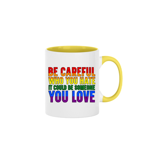 A yellow ceramic mug with rainbow coloured text that reads 'Be careful who you hate it could be someone you love'
