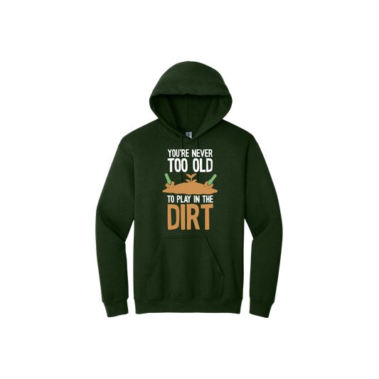 Green unisex hoodie with text that reads 'You're never too old to play in the dirt' along side graphics of a mound of dirt with two gardening trowels.