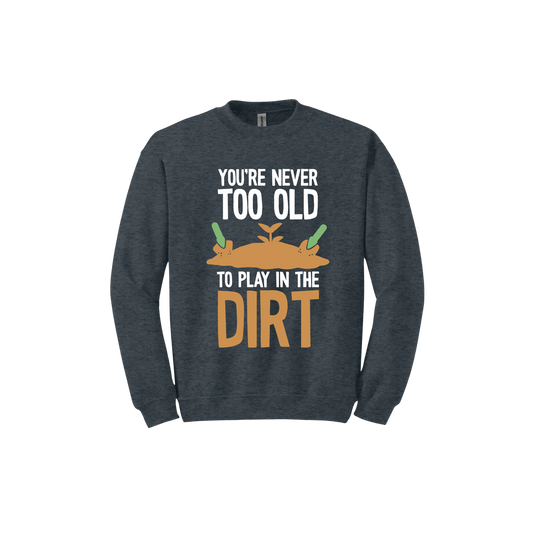 Dark heather unisex sweatshirt with text that reads 'You're never too old to play in the dirt' along side graphics of a mound of dirt with two gardening trowels.